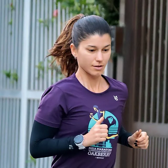 Maria Camila correndo com camiseta roxa durante um treino