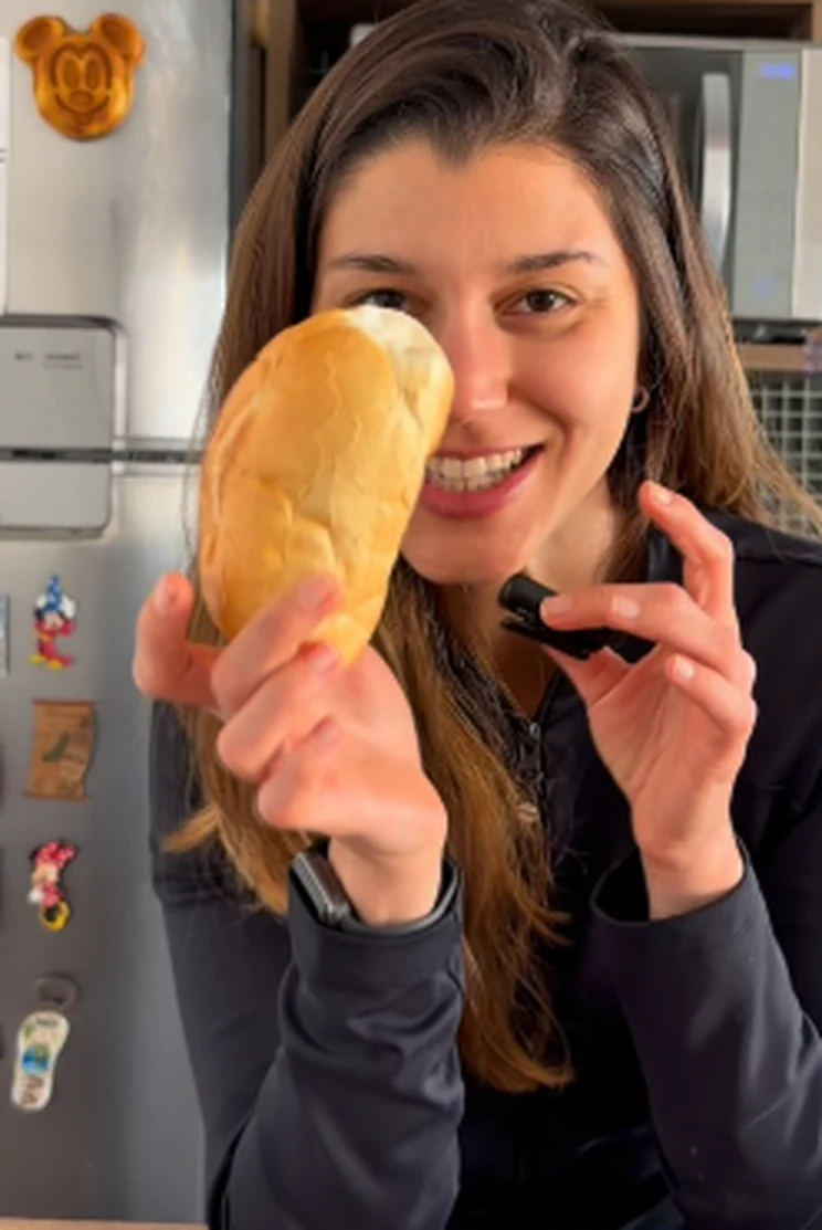 Maria Camila sorrindo e apresentando um alimento na cozinha